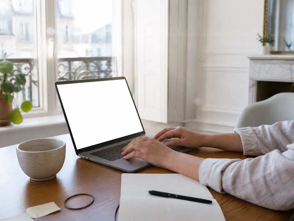 Bureau lumineux avec ordinateur portable, carnet et tasse, plante sur le rebord